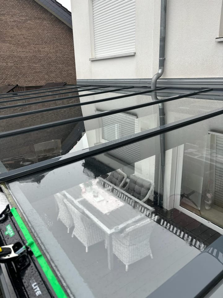 Frisch gereinigtes Glasdach einer Terrassenüberdachung in Oelde, in dem sich die Terrassenmöbel klar spiegeln